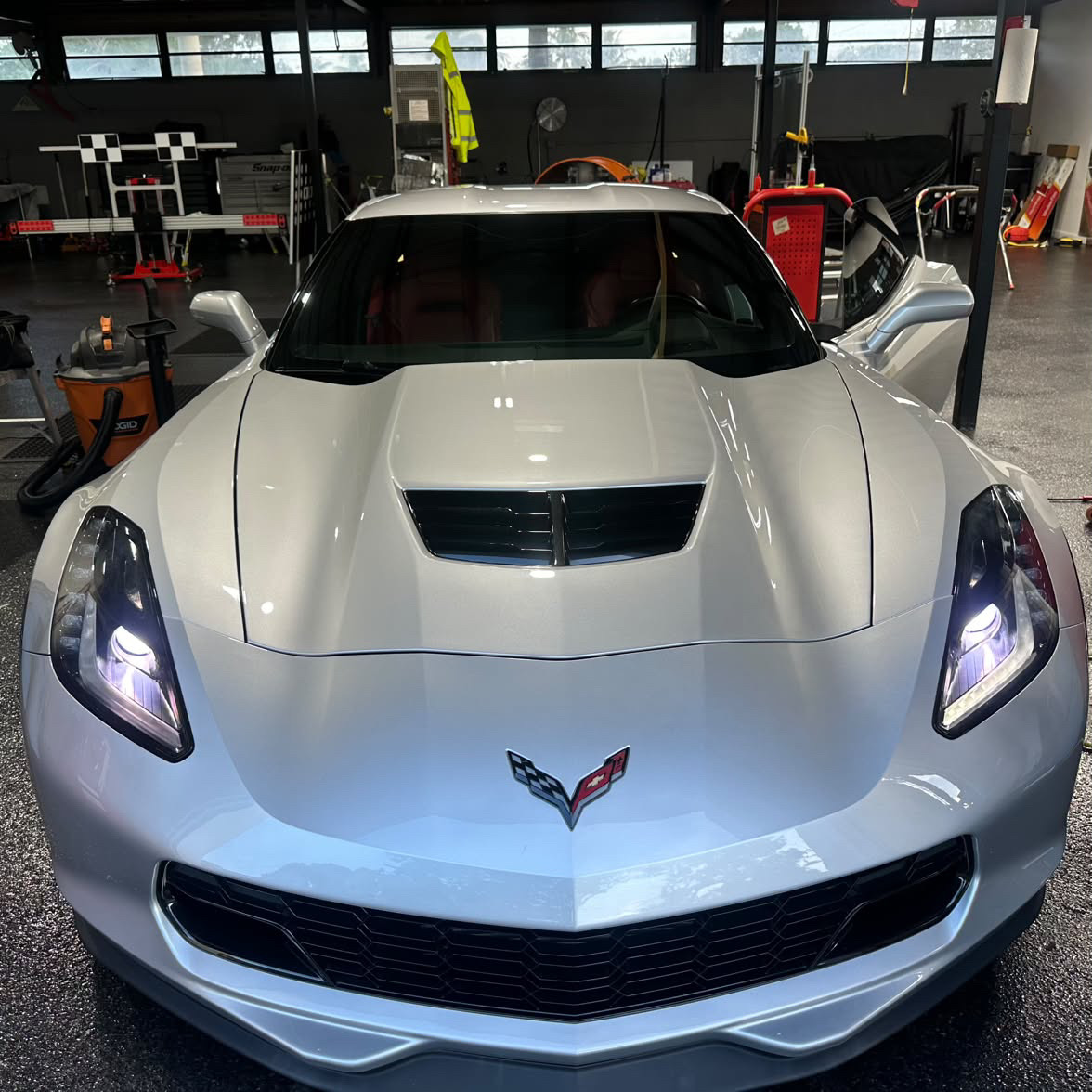 White sports coupe in the bay for windshield replacement and camera recalibration