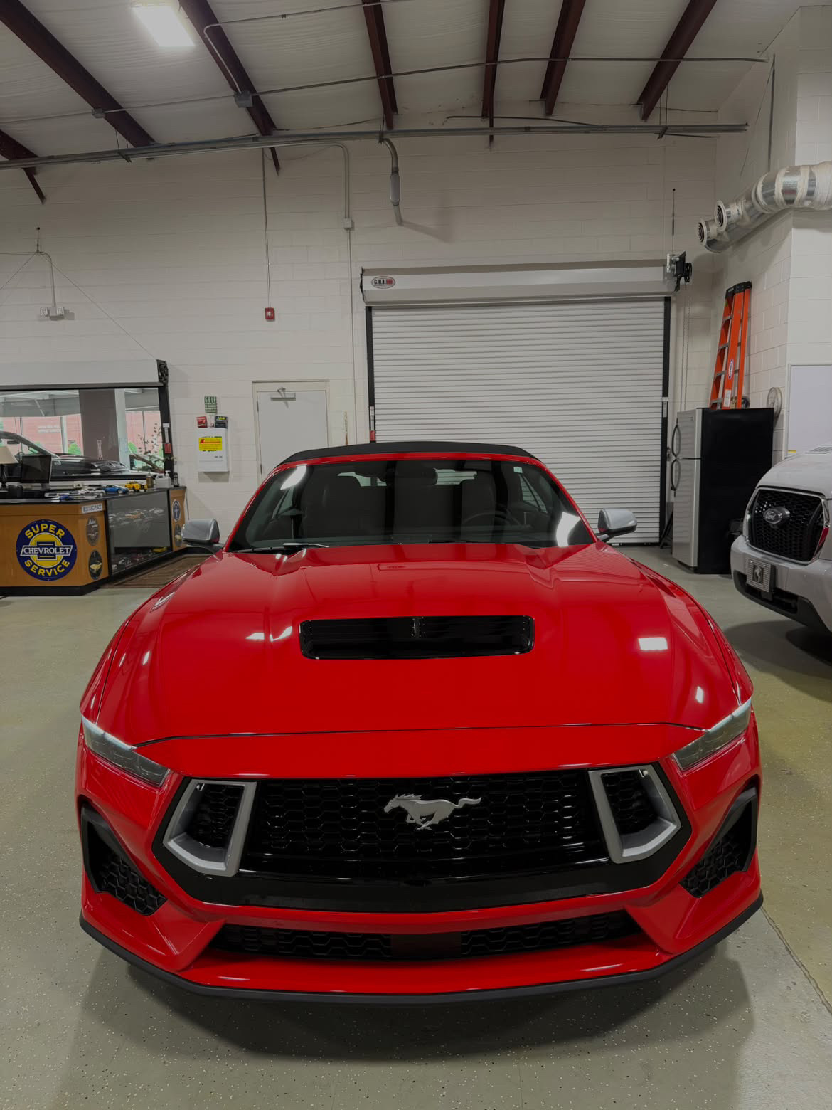 Red sports car in the service bay after a fresh windshield replacement